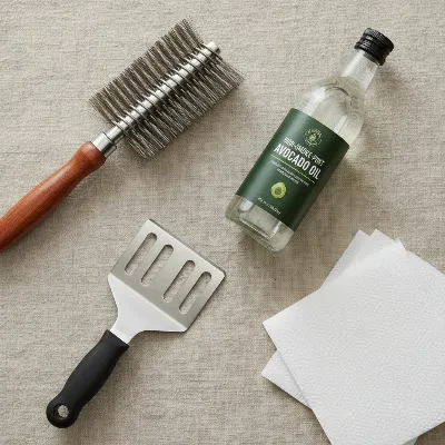 A collection of grill cleaning tools, including a brush, scraper, and oil bottle, for cast iron grates